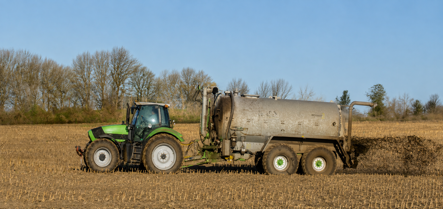 Tractor pulling a liquid application tank across a harvested Central Texas field